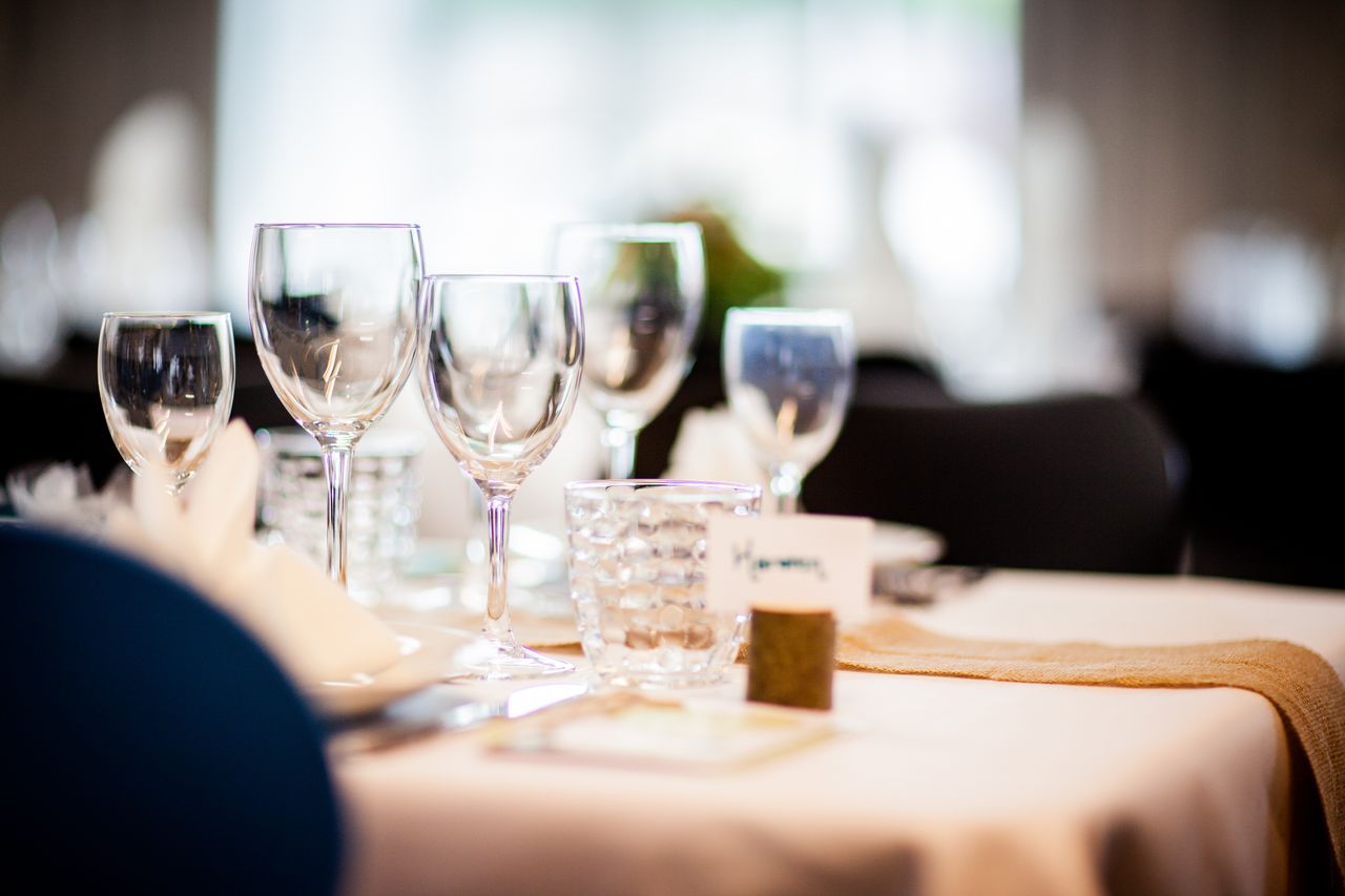 Elegant table setting with wine glasses and decor in softened light, perfect for formal dining or weddings.